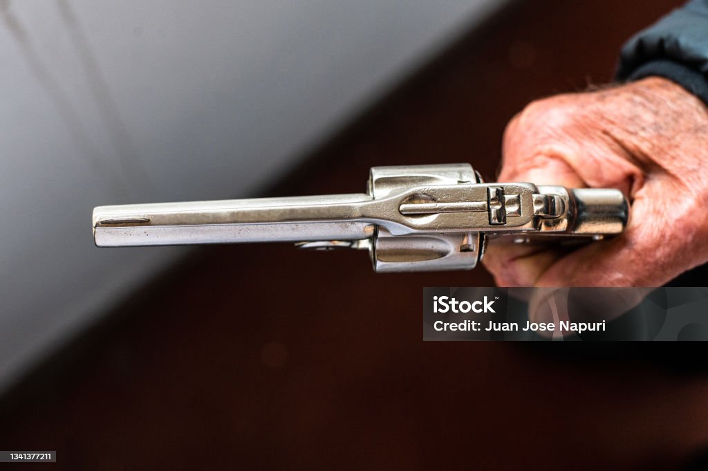 An old hand holding an antique revolver in a shooting position. An old hand holding an antique revolver in a shooting position Gun Stock Photo