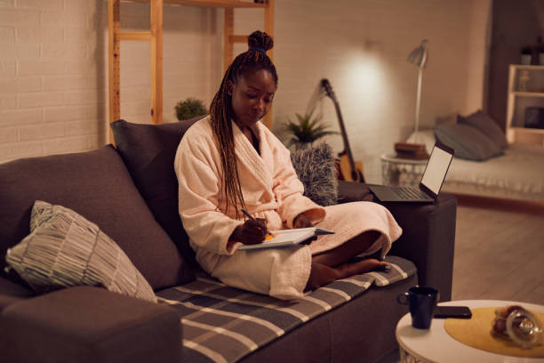 istock Young African American woman writing notes while working at home late ant night. 1341378739