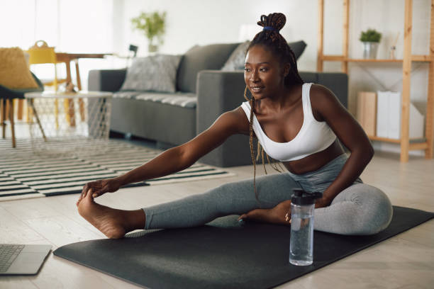 istock Young African American female athlete doing stretching exercises while warming up during home workout. 1341378789