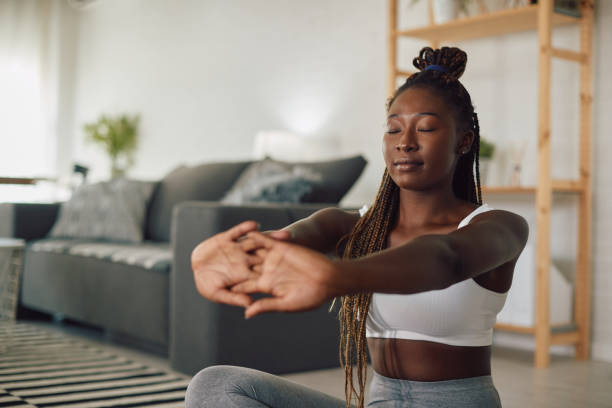 istock Black female athlete doing breathing exercises while practicing Yoga at home. 1341378811