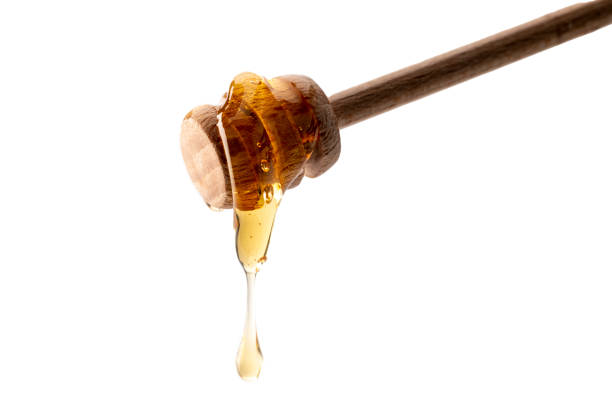 istock Honey dripping from wooden honey spoon 1341386139