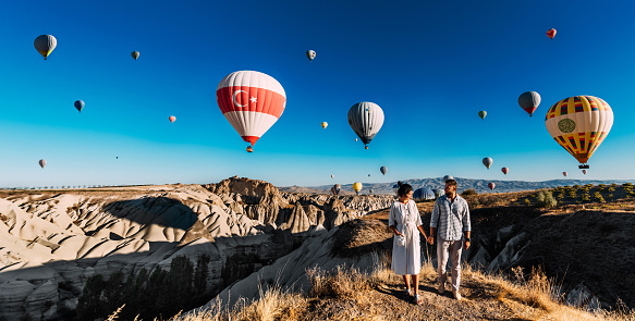 Viaje a los lugares turísticos de Turquía. Una pareja enamorada se alza sobre el fondo de globos en Capadocia, panorama. Viaje a Turquía. Vacaciones en Turquía. Viaje de luna de miel. Capadocia. Espacio de copia photo