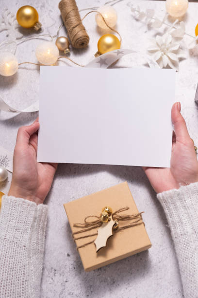 istock Christmas composition, female hands hold empty postcard. Christmas decoration in white color. 1341388010