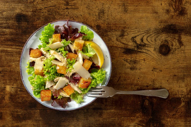 istock Chicken Caesar salad, shot from above on a dark rustic wooden background 1341389255