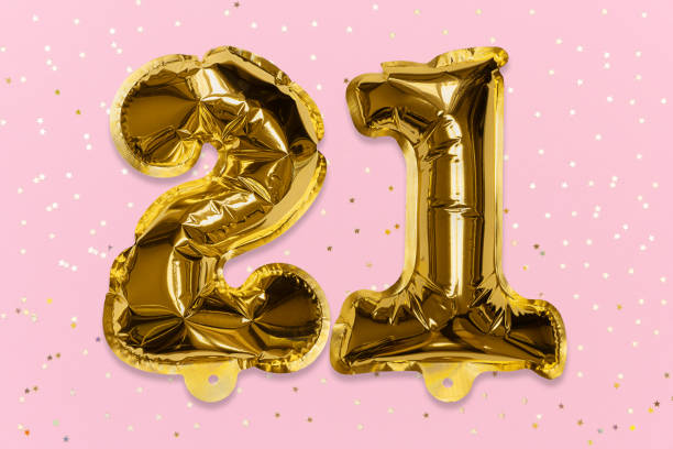 The number of the balloon made of golden foil, the number twenty-one on a pink background with sequins. The number of the balloon made of golden foil, the number twenty-one on a pink background with sequins. Birthday greeting card with inscription 21. Numerical digit, Celebration event, template. 21st birthday stock pictures, royalty-free photos & images