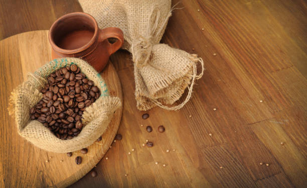 istock Coffee beans in sack, wooden backdrop 1341395802