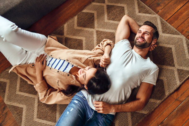 Family at home Young dreaming couple lie on the floor on the carpet at home. A married couple is relaxing in the living room. family at home stock pictures, royalty-free photos & images
