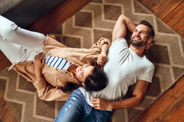 Young dreaming couple lie on the floor on the carpet at home. A married couple is relaxing in the living room.