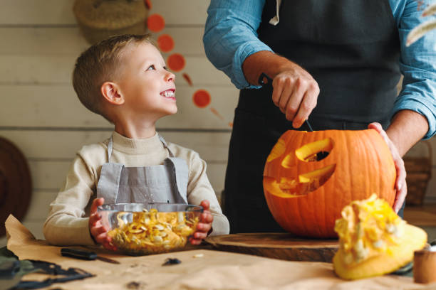istock Son and dad making Jack-o-Lantern together at home, carving Halloween pumpkin 1341400140