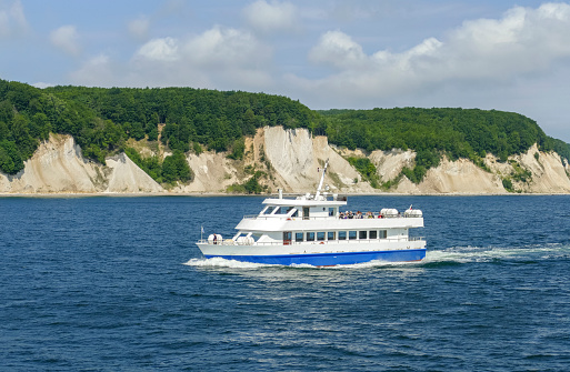 Sunny scenery including a tourist boat around the chalk cliffs at island of Ruegen in Germany