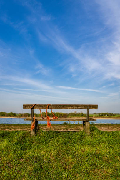 The River Rhine in Rheinberg, North Rhine-Westphalia, Germany A bench with a view towards the River Rhine on the dyke in Orsoy, North Rhine-Westphalia, Germany rheinberg illumination stock pictures, royalty-free photos & images