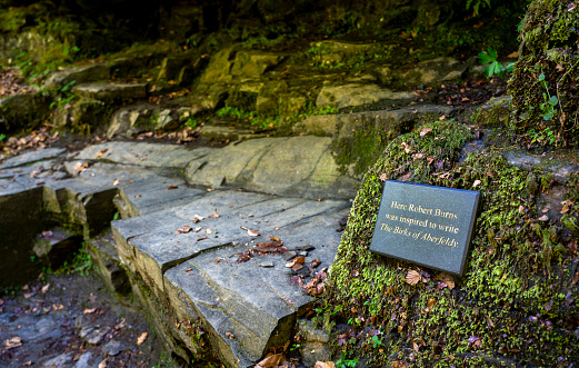 A plaque for Robert Burns at the seat he used at the Falls of Moness, Birks of Aberfeldy amongst the trees of Moness Dun Wood in the Scottish Highlands, UK.