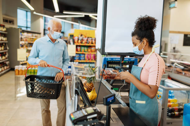 istock Employee at checkout serving senior citizen with face mask 1341406918