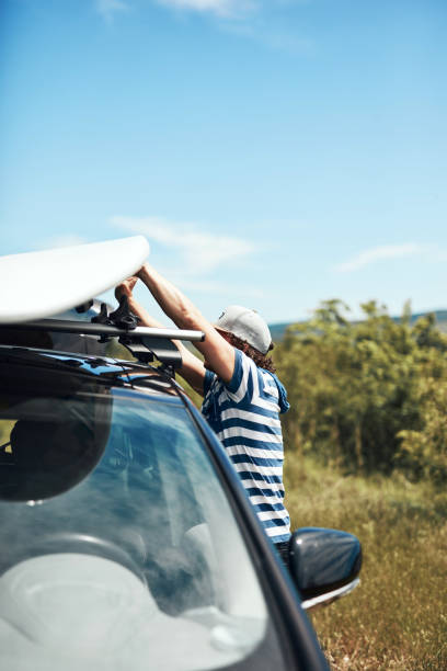 istock Windsurfer and camper packing and unpacking from a car in nature. 1341409927