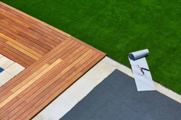 Artificial grass turf installation in deck garden with tools and joint roll