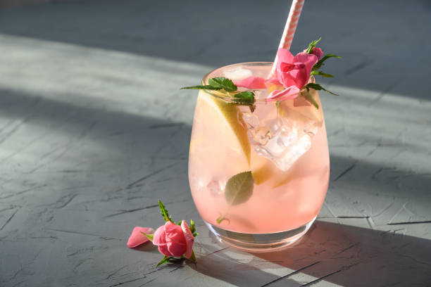 frischegetränk oder limonade mit zitrone und rosen mit sonnigem schatten. - roséwein stock-fotos und bilder