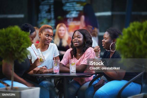 Happy African American Women, friends sitting together at the outdoor restaurant at summer day