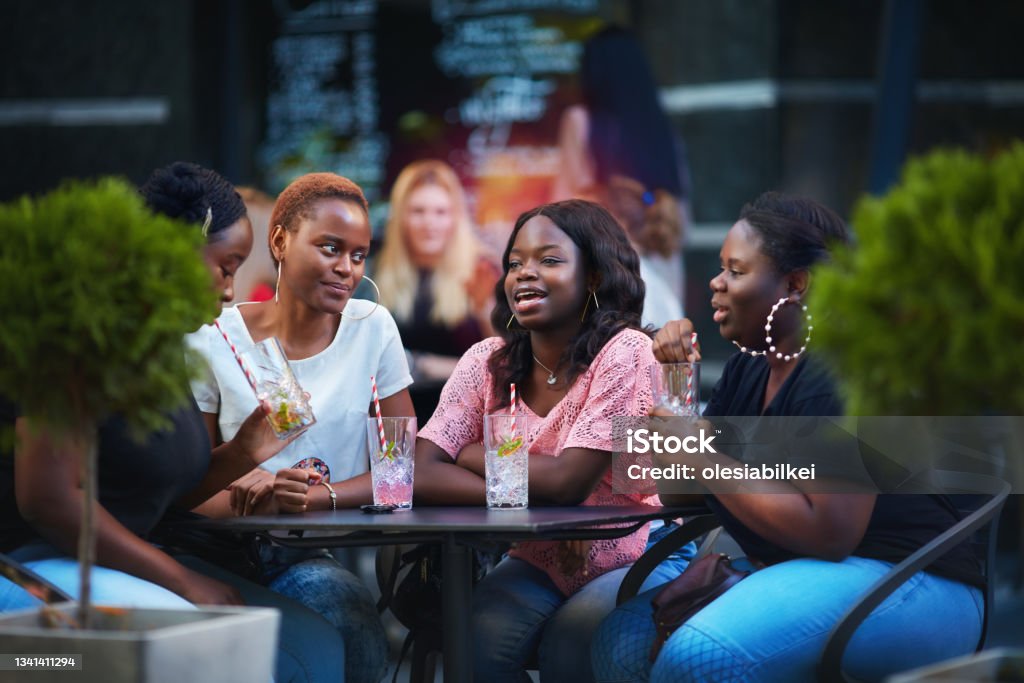 Happy African American Women, friends sitting together at the outdoor restaurant at summer day African-American Ethnicity Stock Photo