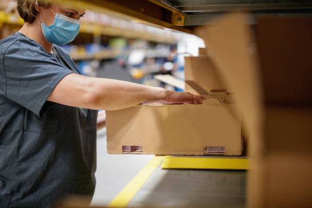 istock Female warehouse worker holding cardboard box and picking items by the rack 1341412471