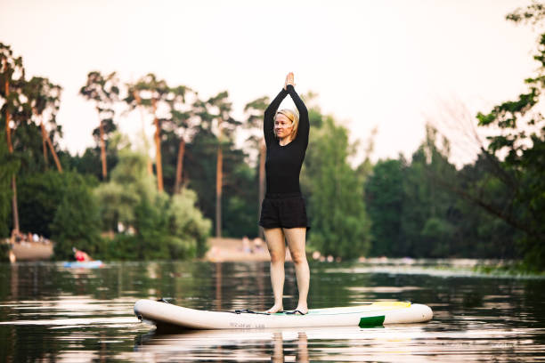 istock Young woman practicing yoga on sup board 1341412928