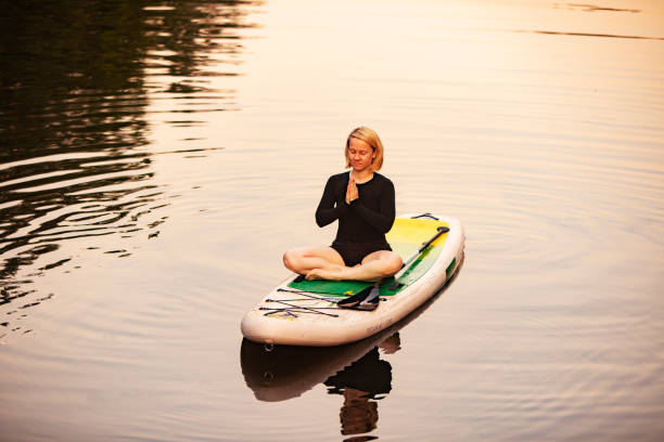 istock Young woman practicing yoga on sup board 1341412938