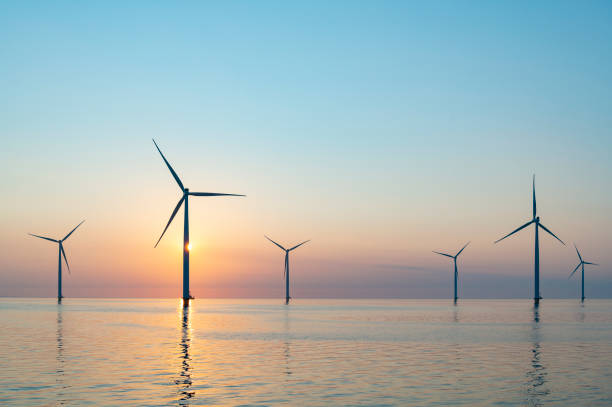 Wind turbines in an offshore wind park producing electricity during sunset. stock photo