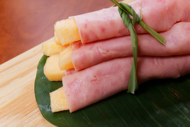 Ham rolls wrapped with melon on a banana leaf and wood background.