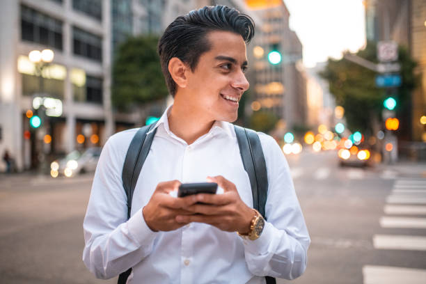 maschio ispanico sorridente alla fine degli anni '20 che controlla il suo smartphone - determination 20s adult attractive male foto e immagini stock