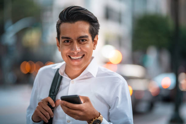 maschio ispanico sorridente alla fine degli anni '20 che controlla il suo smartphone - determination 20s adult attractive male foto e immagini stock