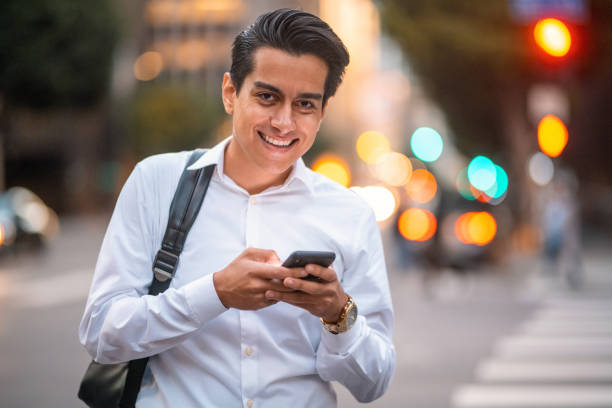 maschio ispanico sorridente alla fine degli anni '20 che controlla il suo smartphone - determination 20s adult attractive male foto e immagini stock