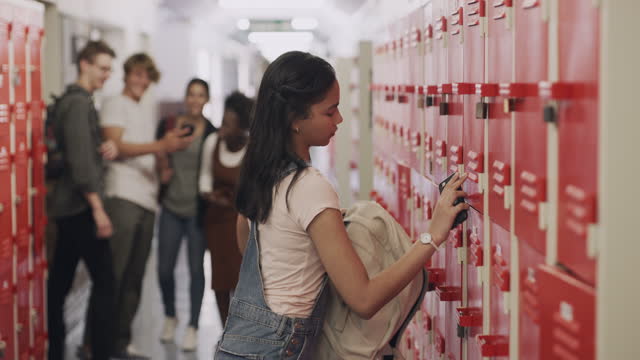 4k video footage of a teenage girl using a smartphone next to her locker and being bullied at high school