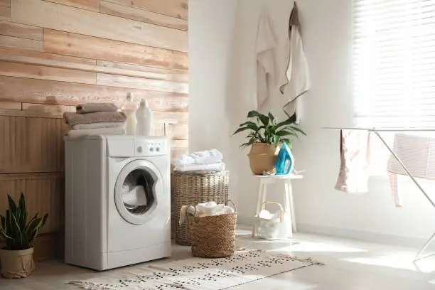 Stylish room interior with modern washing machine