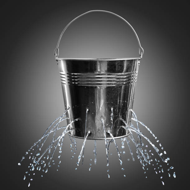 istock Leaky bucket with water on dark background 1341417495
