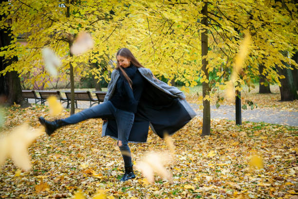 istock Woman kicking autumn leaves 1341418846