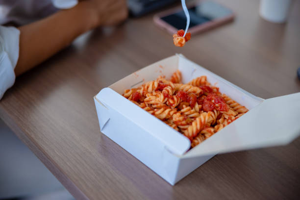 Eating take out pasta straight from the box on lunch break at the office desk