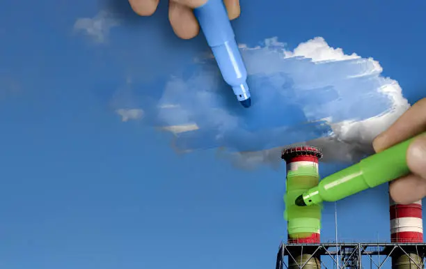 Photo of Hands painting blue and green pollution from a chimney