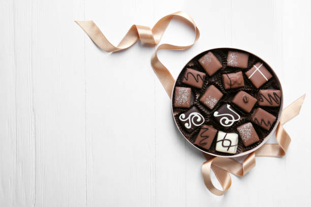 delicious chocolate candies in box on white wooden table, flat lay. space for text - treated wood imagens e fotografias de stock