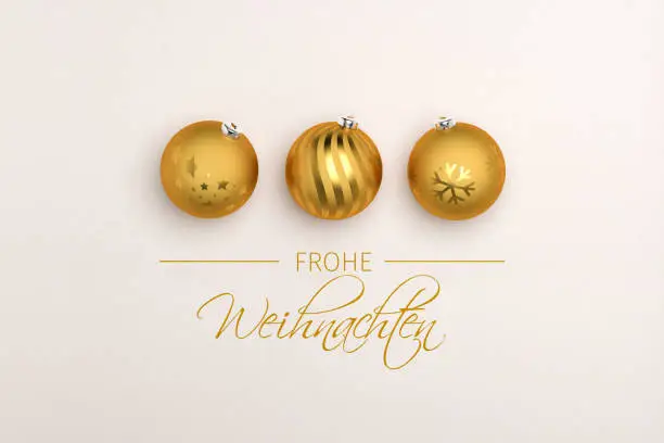 Three golden christmas baubles on paper background. German Message "Frohe Weihnachten" (Merry Christmas) below.