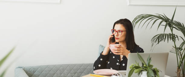 istock Beautiful woman sits in a cafe, drinks coffee, works on a computer and uses a phone 1341420712