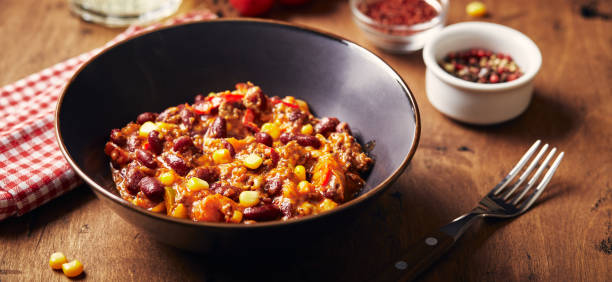 chili con carne with ground beef, beans and corn in dark bowl on wooden background. mexican and texas cuisine - chili food bowl ready to eat imagens e fotografias de stock