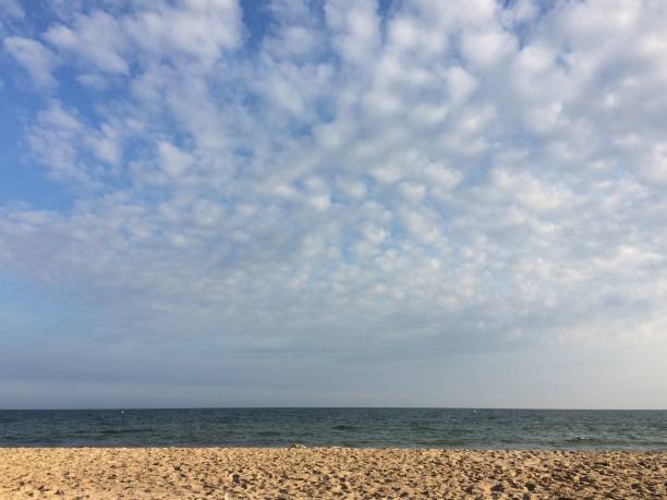 Striking scene of sand with late afternoon shadows, clear dark blue sea and blue sky with beautiful altocumulus clouds on southern coast of England
