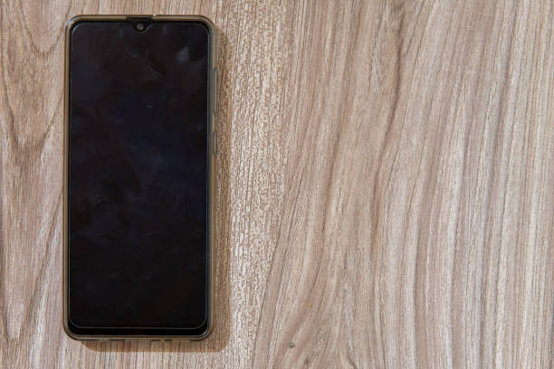 telefone celular moderno olhando em um fundo de madeira impressões digitais visíveis no espaço vazio da tela - surface level dirty wood nobody - fotografias e filmes do acervo