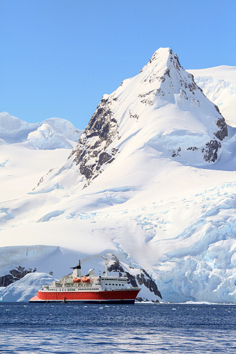 Scenic view of expedition ship in front of steep snowy mountain in Cierva Cove, Trinity Peninsula, Antarctica.