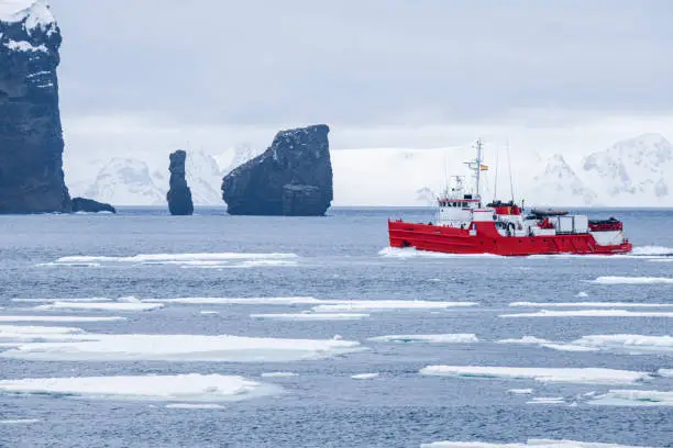 Photo of Oceanographic research vessel in front of spectacular rock formation