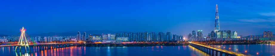Panoramic view across the Han River to the futuristic highrise cityscape of the Jamsil district of central Seoul, South Korea’s vibrant capital city at sunset.