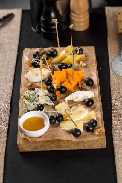 Many kinds of cheese with honey on wooden platter on the table at restaurant stock photo