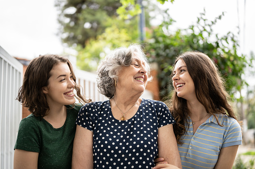 Grandmother and granddaughters looking at each other outdoors