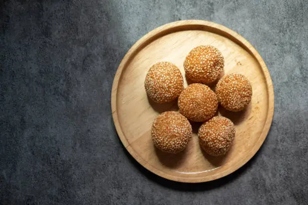 Photo of Fried mung beans stuffed with sesame coated balls on wood dish