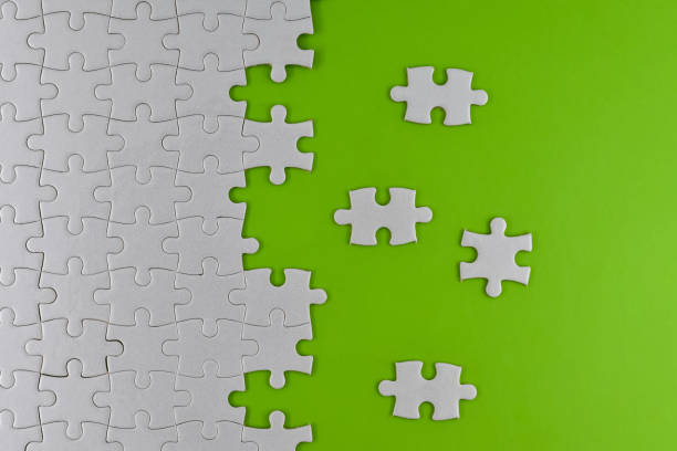 istock Unfinished white puzzle pieces on a green background 1341427893