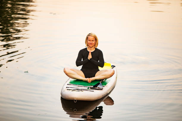 istock Young woman practicing yoga on sup board 1341428600